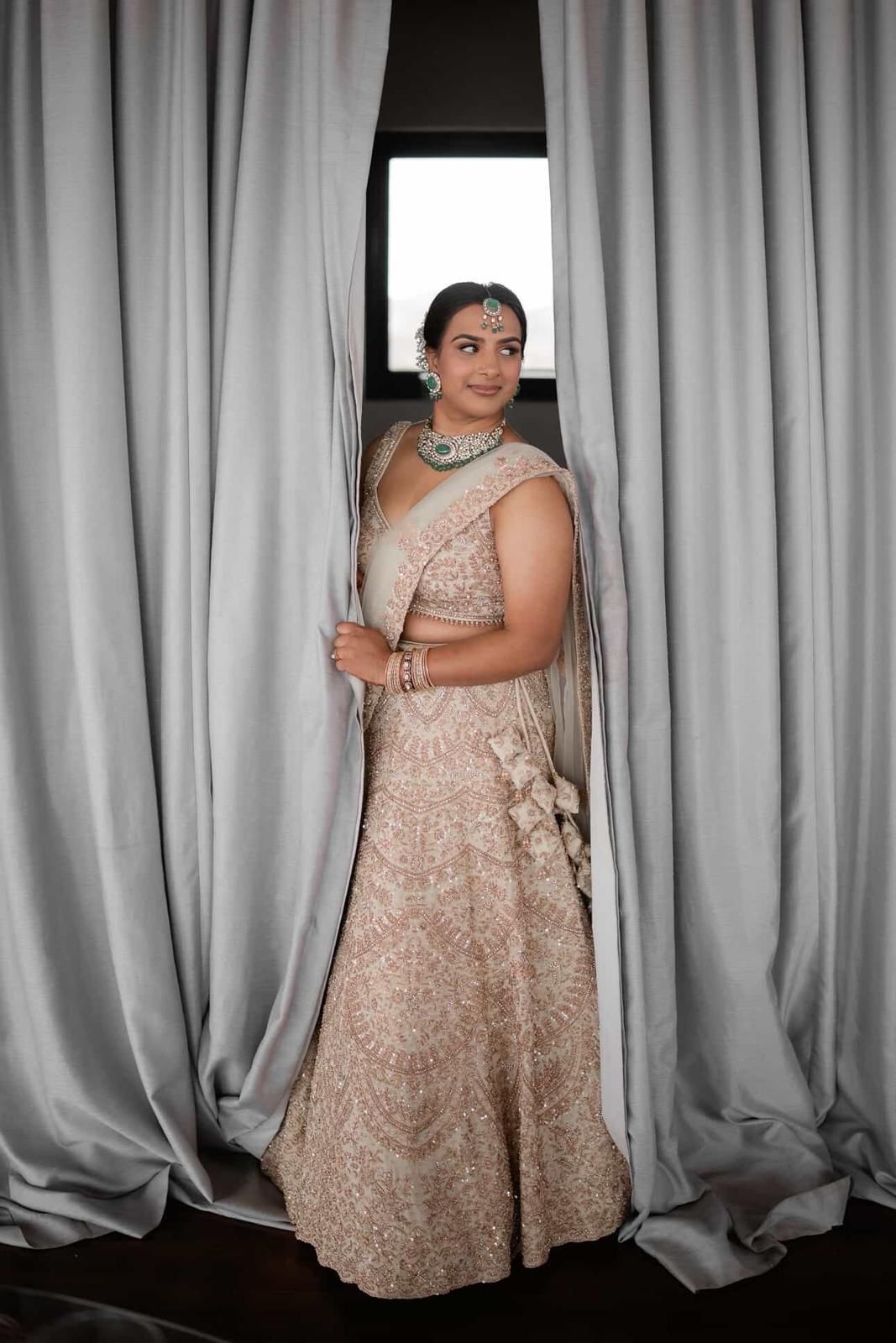 Bride in champagne lehenga with emerald polki bridal set